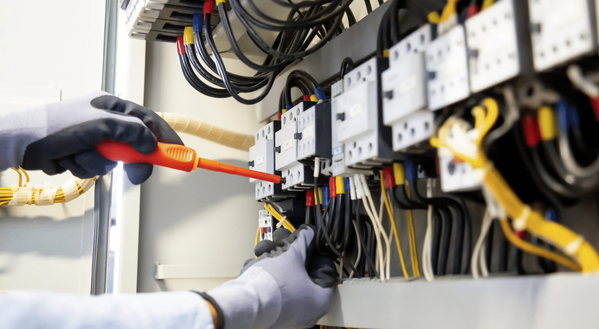 Person using a screwdriver in an electrical panel, symbolizing a government contract opportunity that may be “wired” for a specific vendor.