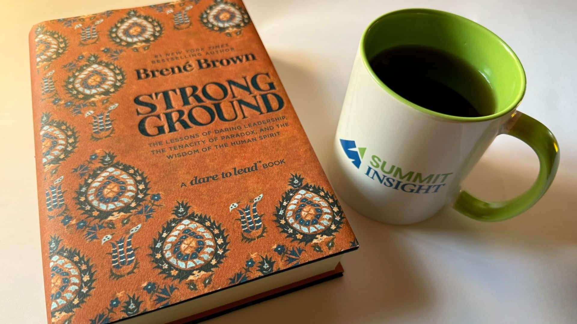 Book Strong Ground by Brené Brown beside a Summit Insight coffee mug, symbolizing trust, reflection, and strong leadership in Federal sales teams.