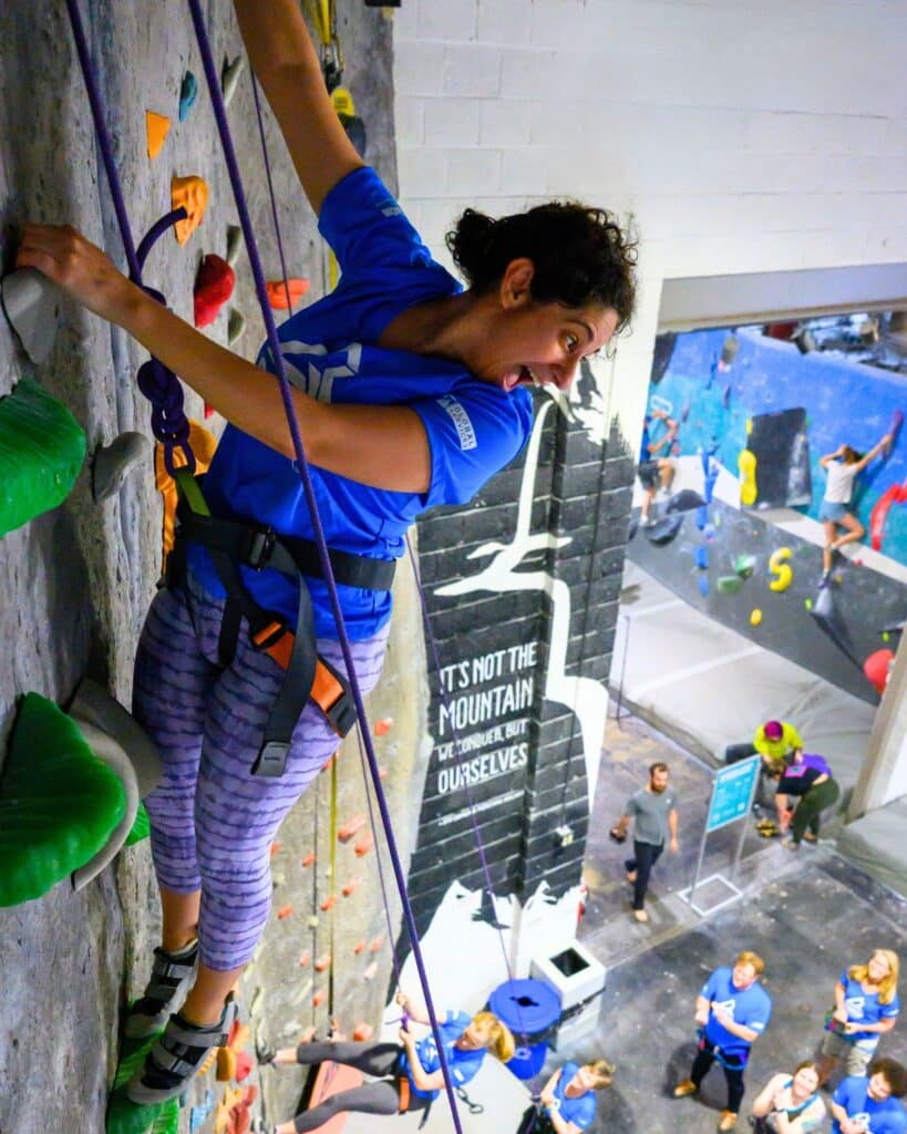 Jessika, a GovCon Rockstar reaching the top of the rock climbing wall on her first ascent